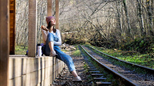 Side view of young woman sitting on railroad track