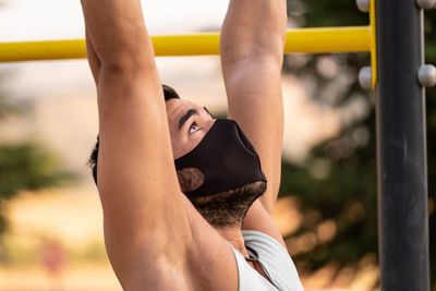 Close-up of young man wearing flu mask exercising outdoors