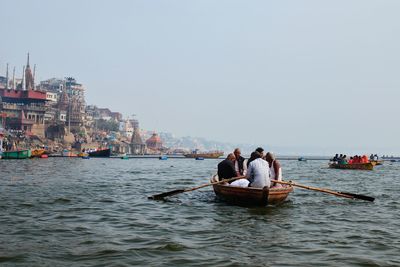 People on boat in sea against sky