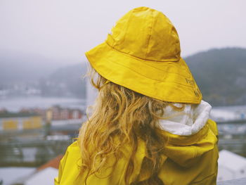 Rear view of woman in yellow warm clothing against sky