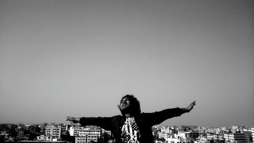 Man with arms raised against sky