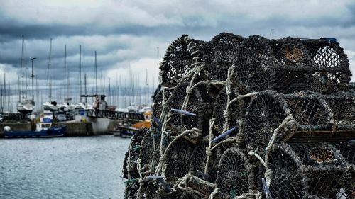 Close-up of fishing net at harbor against sky