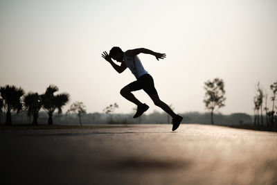 Low angle view of man jumping against clear sky