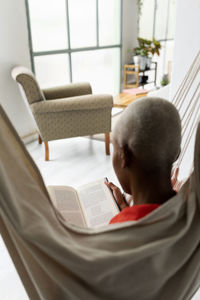 Woman sitting in hammock reading book