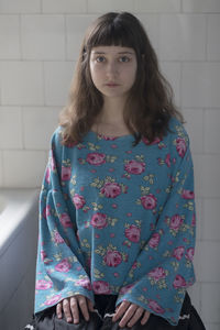 Portrait of woman standing against wall