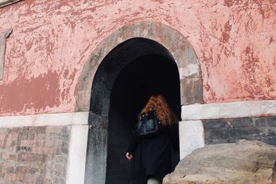 Rear view of woman standing against wall