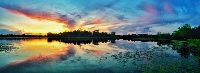 Scenic view of lake against cloudy sky at sunset