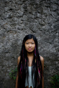 Portrait of beautiful young woman standing against rock