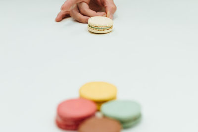 Cropped image of hand playing with macaroons on table