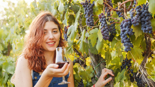 Young girl with glass of wine smile during the harvest in the countryside