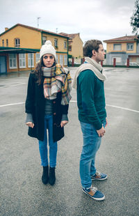 Full length of sad couple looking away while standing on road