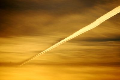 Low angle view of vapor trail in sky during sunset