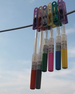 Low angle view of colorful tubes hanging to clothesline against sky