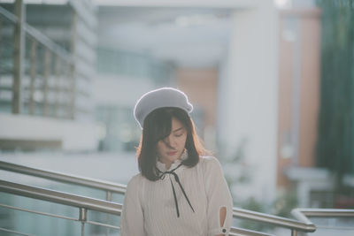 Close-up of young woman against railing in city