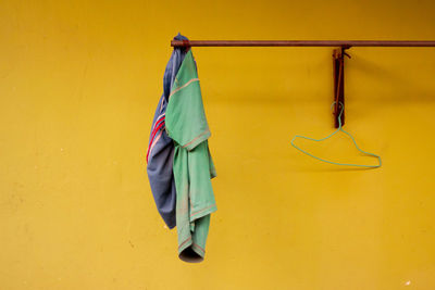 Close-up of clothes hanging on yellow wall