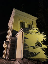 Low angle view of cross by building against sky at night