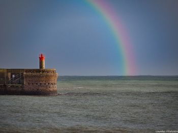 Scenic view of rainbow over sea against sky