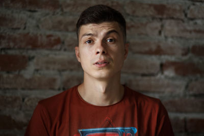 Portrait of young man standing against wall