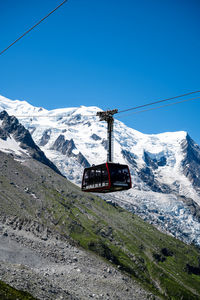 Overhead cable car on snowcapped mountains against clear blue sky