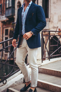 Low section of man standing on railing