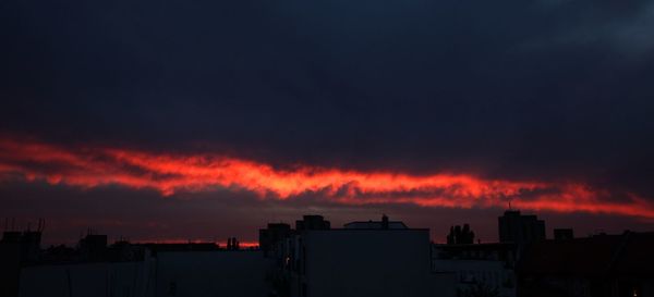 Silhouette buildings against dramatic sky during sunset