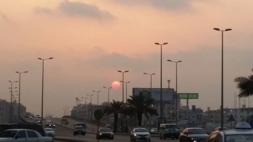 Traffic on road against sky during sunset