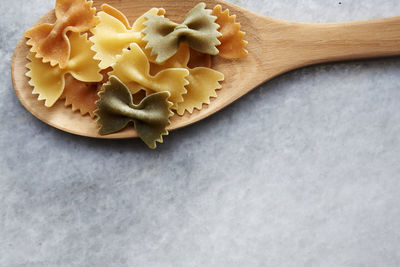 Close-up of farfalle in wooden spoon on marble