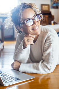 Portrait of young woman wearing sunglasses while sitting on table