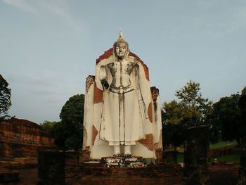 Low angle view of statue by building against sky