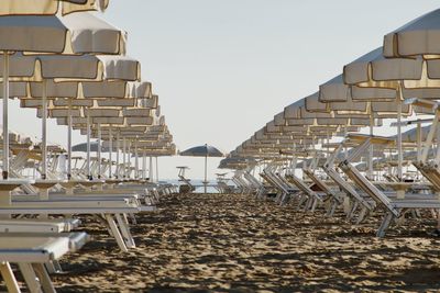 Empty chairs on beach against clear sky