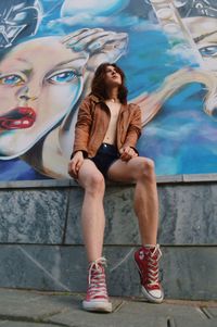 Full length of teenage girl sitting on wall