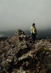 Rear view of man standing on rock against clear sky