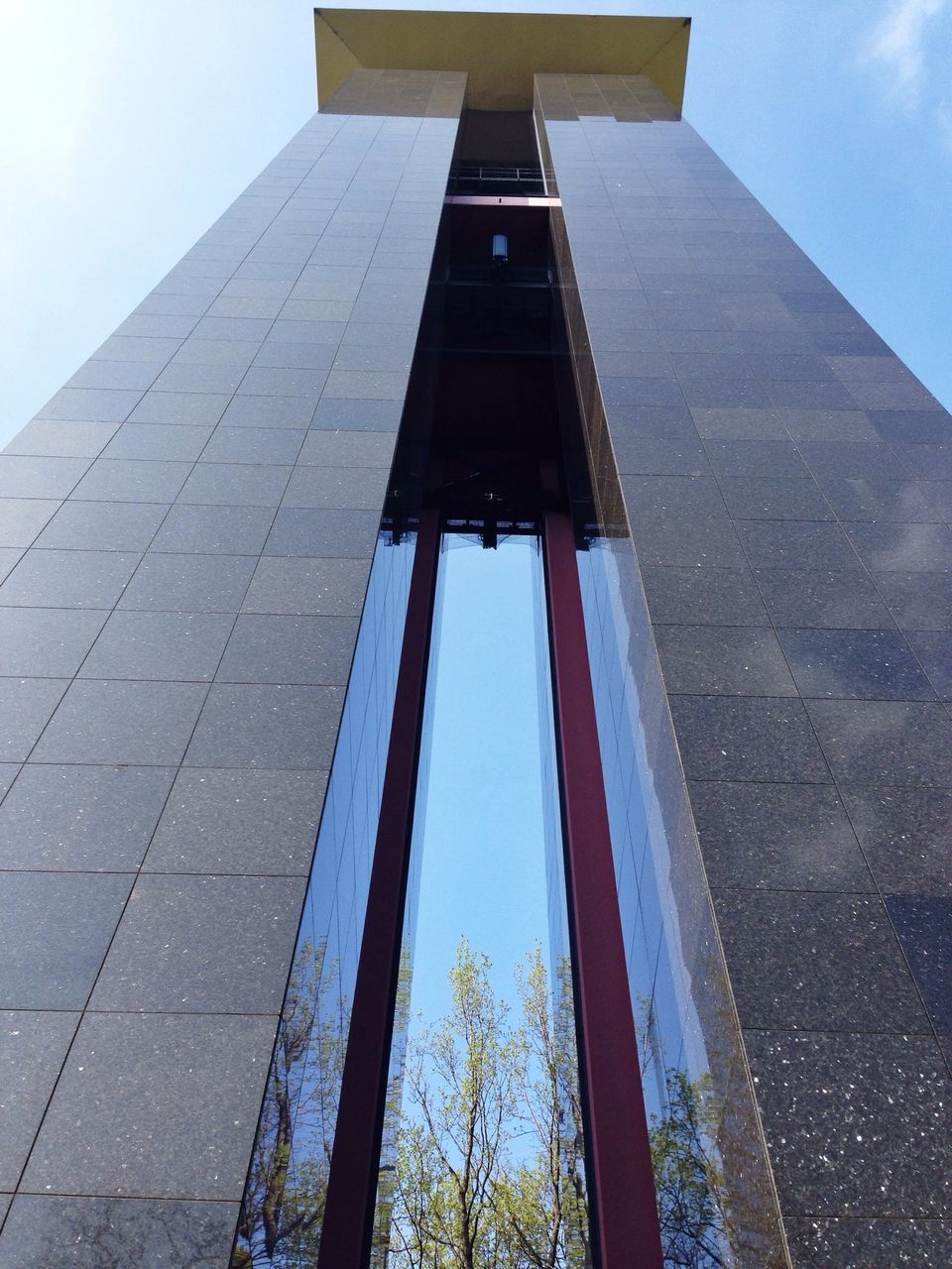 architecture, built structure, building exterior, low angle view, sky, city, tall - high, tower, day, modern, sunlight, building, outdoors, blue, flag, no people, office building, reflection, skyscraper, clear sky