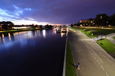 High angle view of illuminated city by river against sky