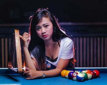 Portrait of young woman smiling while sitting on table