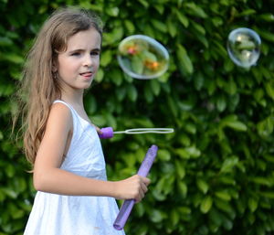 Portrait of girl playing with bubble wand