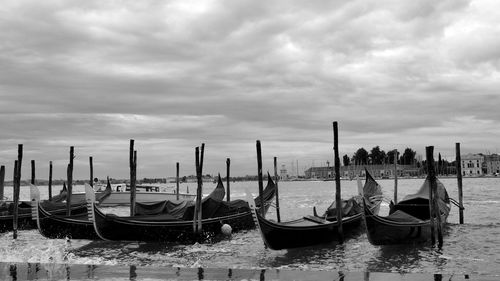 Boats moored in canal against cloudy sky