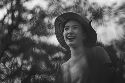 Low angle view of happy woman looking away against trees