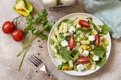 Italian food - salad with gluten free pasta, spinach, tomatoes, beans and feta cheese.