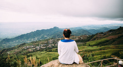 Rear view of woman looking at mountains against sky