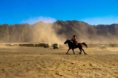 Full length of man riding horse on mountain