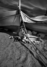 Man and woman sleeping by boat on sand