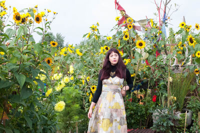 Portrait of young woman standing against plants