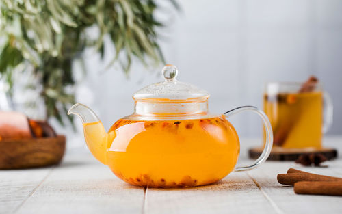 Autumn sea buckthorn tea in a teapot on a white wooden background. 