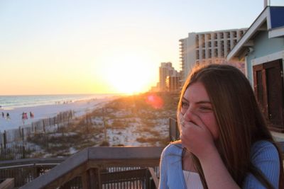 Portrait of woman against buildings in city at sunset