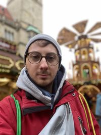 Portrait of young woman standing against building
