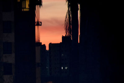 Silhouette buildings against sky at sunset