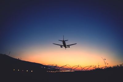 Low angle view of silhouette airplane against clear sky during sunset