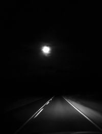 Illuminated road against sky at night