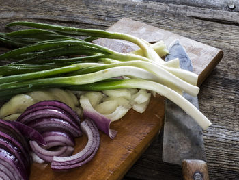 High angle view of scallions and onions on wooden table